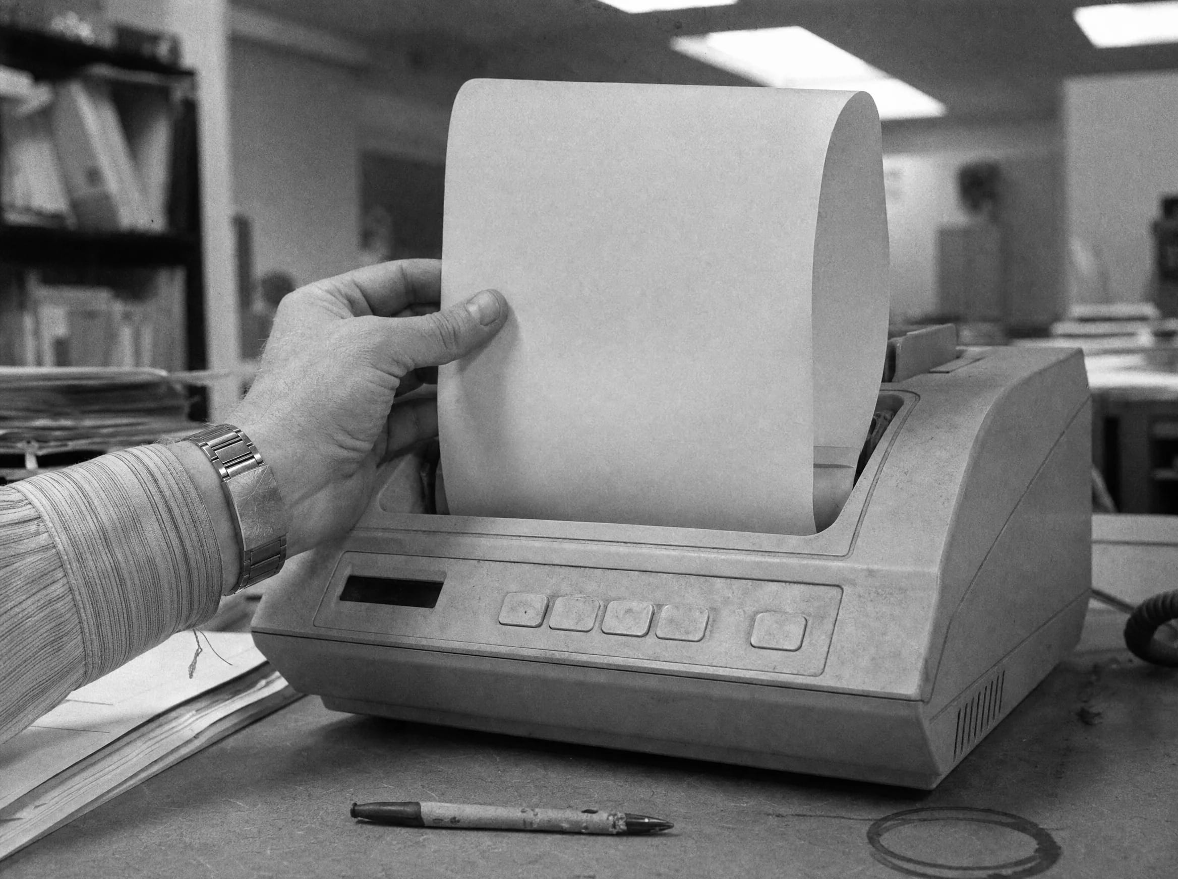 A hand catches a curling fax page as it leaves the machine