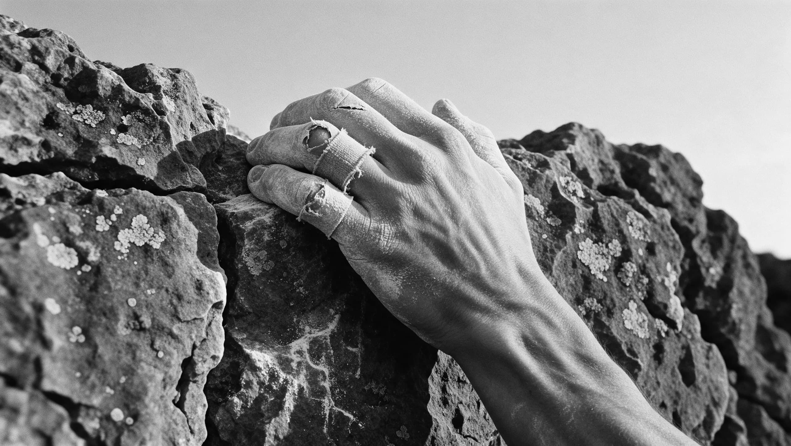 A climber's chalked hand gripping a small edge of rock